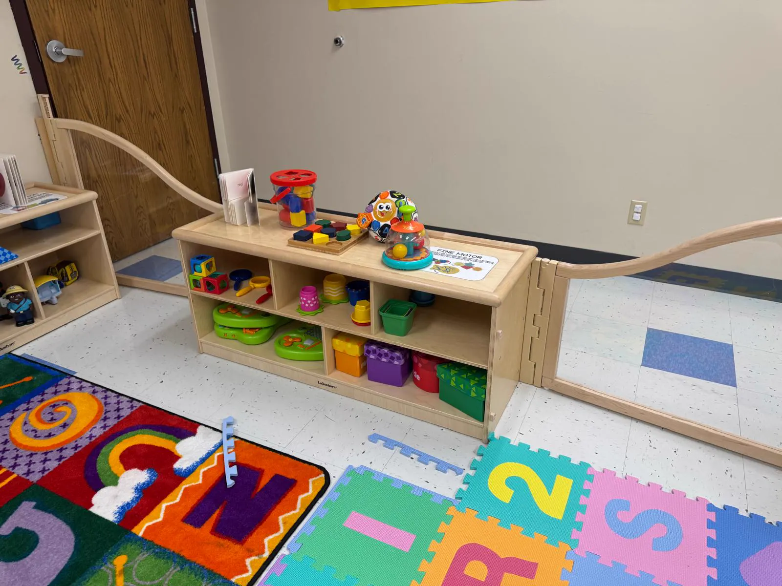 Infant room with colorful soft play mats and low toy shelves