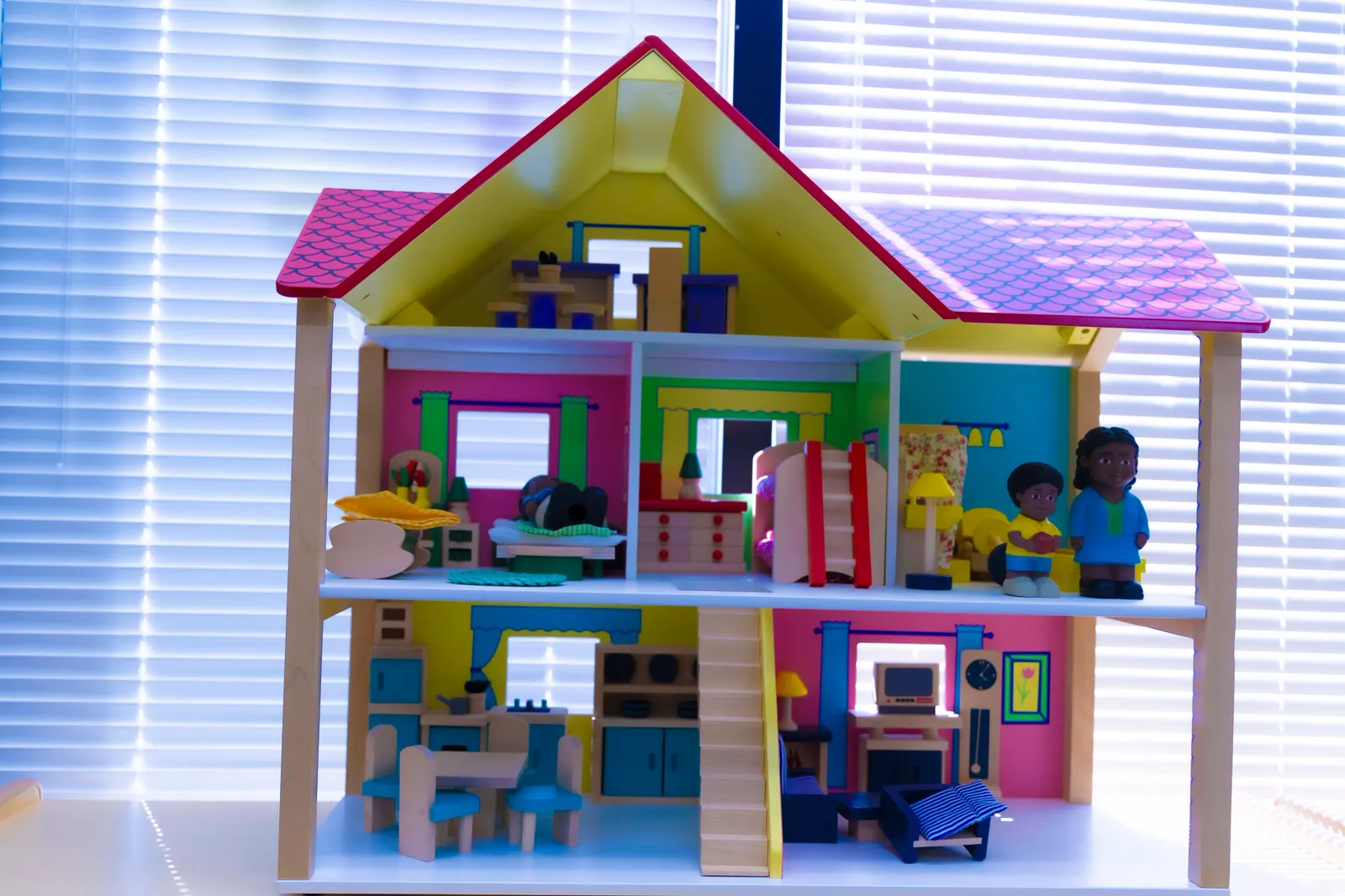 Colorful wooden dollhouse with small figures in a classroom